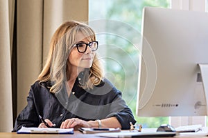 Attractive businesswoman sitting at home and using computer for work