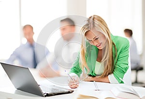 Attractive businesswoman taking notes in office