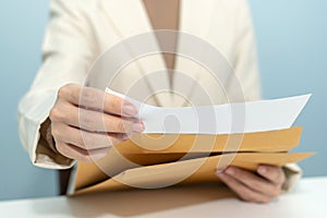 Attractive businesswoman hand open business report from document envelope and working on desk