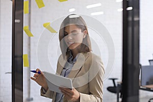 Attractive busness woman post stickers on glass at office and writing on them