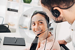 Attractive call center operator smiling and looking at colleague