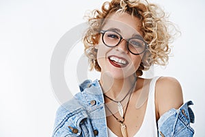 Attractive carefree and lovely hipster woman with blond hair in glasses and lipctick smiling charming at camera and