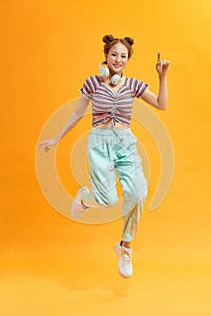 Attractive careless cheerful girl jumping listening bass having fun isolated over bright yellow color background