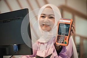 attractive cashier muslim showing edc machine to camera