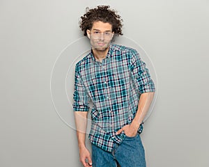 attractive casual guy with glasses in plaid shirt holding hand in pockets