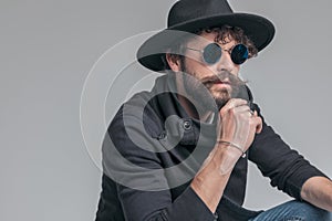 Attractive casual man touching his beard, squatting