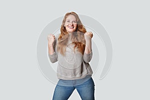 Attractive casual woman with positive facial expression having fun against white studio wall background