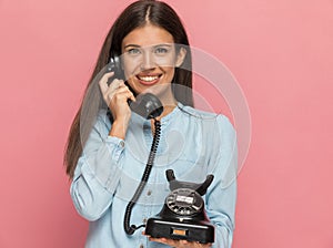 Attractive casual woman talking on an old telephone