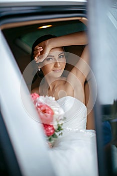 Attractive caucasian bride sitting in car and smile to the camera