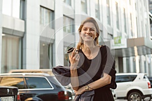 Attractive caucasian girl laughing and feeling happy outside in the urban scenery drinking coffee.Beautiful woman with broad smile