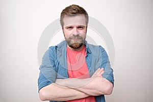 An attractive Caucasian man with a benevolent appearance stands with crossed arms and looks into the camera. White