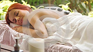 Attractive caucasian woman getting hot stone massage at spa