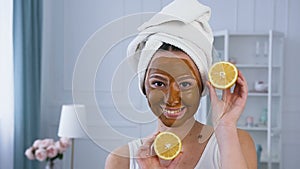 Attractive caucasian woman posing with two half of lemon with brown mask on the face.