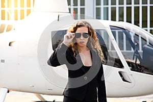 Attractive caucasion business woman with a helicopter in the background. success and luxury concept photo