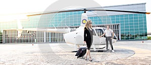 Attractive caucasion business woman with a helicopter and captain in the background. success and luxury concept