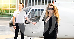 Attractive caucasion business woman with a helicopter and captain in the background. success and luxury concept