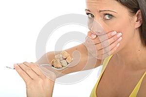 Attractive Cautious Natural Young Woman Holding a Spoonful of Brown Sugar Cubes photo