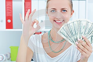 Attractive cheerful female showing many banknotes of one hundred dollars. Winning money prize conce