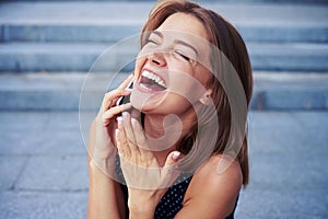 Attractive cheerful female speaking on the phone and laughing si