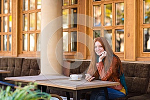 Attractive cheerful woman sitting with cellphone in outdoor cafe