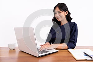 Attractive cheerful young business woman working on laptop and smiling while sitting.