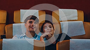 Attractive cheerful young caucasian couple laughing while watching film in movie theater. Lifestyle entertainment concept