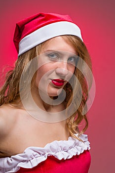 Attractive Christmas girl in santa hat on a red