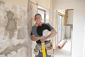 Attractive and confident constructor carpenter or builder man with ear protection gear working happy at industrial construction si