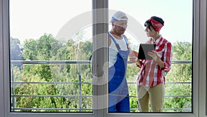 Attractive Construction worker and pretty female assistant make measurements of windows using measuring tape and make