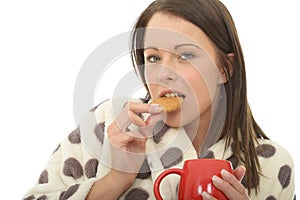 Attractive Cosy Relaxed Happy Young Woman Eating a Biscuit with Tea