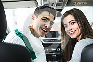 Attractive couple chooses a new car in the showroom, sitting in the car