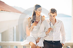 Attractive couple drinking cocktails ,enjoying summer vacation.Smiling,attracted to each other.Flirting and seduction