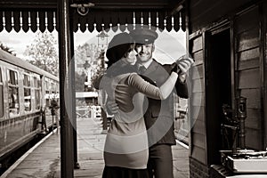 Attractive couple dance on railway station platform with portable record player