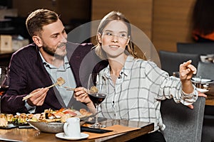 Attractive couple having dinner while woman pointing at something