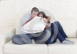 Attractive couple having fun at home enjoying watching television horror movie show