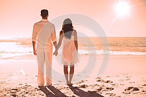 Attractive couple holding hands and watching the waves