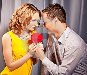 Attractive couple of lovers. Man presents flower.