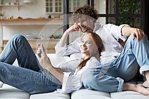 Attractive couple relax on couch using digital tablet together at home