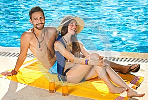 Attractive couple relaxing alongside a pool.