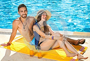 Attractive couple relaxing alongside a pool. photo