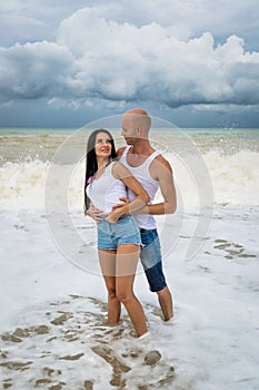 Attractive couple posing in sea foam in time of surf