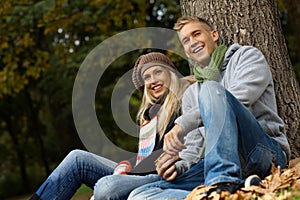 Attractive couple sitting on ground in autumn park