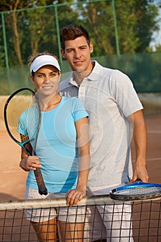 Attractive couple smiling on tennis court