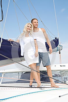 Attractive couple standing on sailing boat - sailing trip.