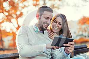 Attractive couple talking and looking at digital tablet.