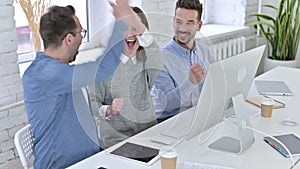 Attractive creative team celebrating success on desk top