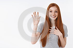 Attractive cute lovely redhead young girl blue eyes raise one hand hold palm heart promise give oath pledge loyalty photo