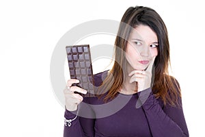 Attractive cute young woman with bar chocolate looking with temptation