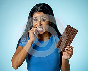 Attractive cute young woman with big bar of chocolate looking at it happy with temptation