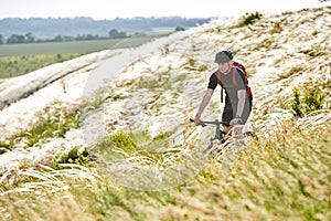 Attractive cyclist riding the bicyclist on the beautiful summer mountain trail.